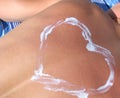 The sunburned back of a tanning man. Heart pattern on the back, made with sunblock. The concept of a healthy holiday, care for