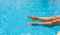 Sunburned female legs, splashes, clear turquoise pool water