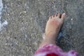 Sunburnt foot of a woman in shallow transparent ocean waters. Sand and shells.