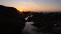 Sunburst behind rocks in silhouette at sunset on beach in Portugal