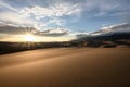 Sunburst And Cloudy Mountains Over Sand Dunes Royalty Free Stock Photo