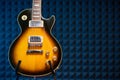 Sunburst electric guitar standing over acoustic foam panel background Royalty Free Stock Photo