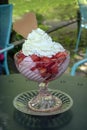 Sundae from ice cream with fresh strawberries and whipped cream in a glass bowl on a table in a street cafe, copy space, selected Royalty Free Stock Photo