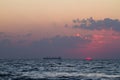 Sundawn on the Black Sea, sun disk appear on horizon with some clouds, early morning, gentle waves on water surface, cargo ship Royalty Free Stock Photo