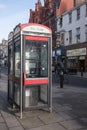 Exterior shot of a telephone kiosk on the pavement in a town. Modern design