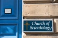 Exterior sign by the entrance door of the Church of Scientology showing signage, branding and logo