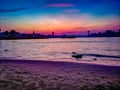 Sundown over the sand beach of the riverside of the river Rhein in Cologne with sky and sunlight reflections and bridge