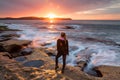 Sunflare kissing the shoulder of a woman watching sunrise by the ocean