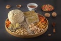 Sunflower halva sprinkled with chopped nuts and raisins on a wooden platter with pistachios, peanuts, dried apricots, candied