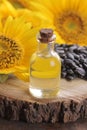 Sunflower oil in a glass bottle and sunflower seeds on a wooden stand next to beautiful yellow sunflowers on a brown backgr Royalty Free Stock Photo