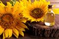 Sunflower oil in a glass bottle on a wooden stand next to beautiful yellow sunflowers on a wooden background Royalty Free Stock Photo