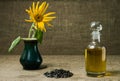 Sunflower oil in a glass decanter, a bunch of sunflower seeds and a sunflower in a vase on a background of burlap Royalty Free Stock Photo