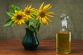 Sunflower oil in a glass decanter and a sunflowers in a vase on a background of burlap Royalty Free Stock Photo