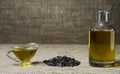 Sunflower oil in a glass gravy boat, in a bottle, and a handful of sunflower seeds on the background of burlap