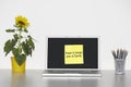 Sunflower plant on desk and sticky notepaper with French text on laptop screen saying Passer le temps avec la famille Royalty Free Stock Photo