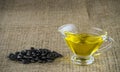 Sunflower seed oil in a glass gravy boat and a handful of sunflower seeds on the background of burlap. Royalty Free Stock Photo