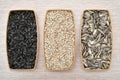 Sunflower seeds in the three separate wooden dishes on the wooden table