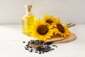 Sunflowers, bottle of oil and seeds on white wooden table Royalty Free Stock Photo