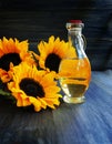 Sunflowers and bottle of oil on a wooden table