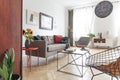 Sunflowers by a comfy sofa with cushions in a bright living room interior with diverse style of furniture and decorations.