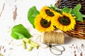 Sunflowers in the wicker basket, scissors and threads on the white rustic table. Gardening, homemade bouquet