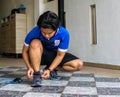 An athletic young man tying up his sport shoelace before exercise at home. Fitness, sports and healthy lifestyle concept