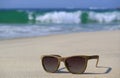 Sunglasses on the beach with blurry splashing waves in background