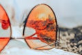 Sunglasses on a beach with reflection of summer beach with black sand, sun and sea Royalty Free Stock Photo