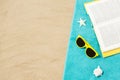 Sunglasses and book on beach towel on sand Royalty Free Stock Photo