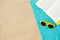 Sunglasses and book on beach towel on sand Royalty Free Stock Photo