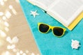 Sunglasses and book on beach towel on sand Royalty Free Stock Photo