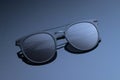 Sunglasses close-up on a dark gray glossy background. Women`s black glasses with a gradient. Polarized round lenses of eyeglass. Royalty Free Stock Photo