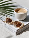 Sunglasses and coffee on a magazine with palm leaf shadow. Royalty Free Stock Photo