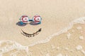 Sunglasses with flag of Turkish Republic of Northern Cyprus on a sandy beach. Nearby is a sea lightning and a painted smile.