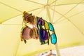 Sunglasses are hanging on an umbrella under the sun, a bright summer day on the beach at the sea Royalty Free Stock Photo