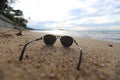 Sunglasses on the sand in the empty seabeach with a sea view