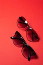 Sunglasses lie on a red background, close-up