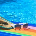 Sunglasses, lilo and hat on the water in hot sunny day. Summer background for traveling and vacation. Holiday idyllic. Royalty Free Stock Photo