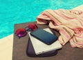 Sunglasses, mobile phone, e-book reader and female scarf near the pool.