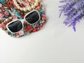 Sunglasses and necklaces made of pearls, placed on fashion veils and violet flowers