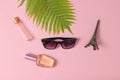 Sunglasses, perfume bottles, a statuette of the Eiffel Tower, fern leaf on a pink pastel background. Minimalism. Flat lay style.