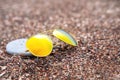 Sunglasses with polarizing lenses with pebble nearby lie on sand, close up.