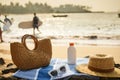 Beach scene with straw bag, sunscreen bottle, on blue towel. Sunglasses rest beside, essentials for sun safety Royalty Free Stock Photo