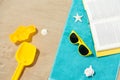 Sunglasses, sand toys and book on beach towel Royalty Free Stock Photo