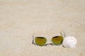 Sunglasses and seashell on beach sand background, summer holiday Royalty Free Stock Photo