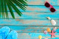 Sunglasses, shells, starfish and slipper on wood background.