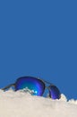 Sunglasses lying in the snow on blue sky background
