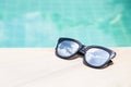 Sunglasses with sky reflection on swimming pool edge with space on blue water background Royalty Free Stock Photo