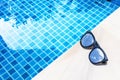 Sunglasses with sky reflection on swimming pool edge with space on blue water background Royalty Free Stock Photo
