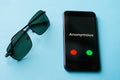 Sunglasses and smartphone with anonymous call lie on a blue surface. The problem of anonymity and espionage Royalty Free Stock Photo